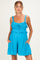 woman wearing a bright blue maternity romper with ruffled straps and pockets, showing her baby bump