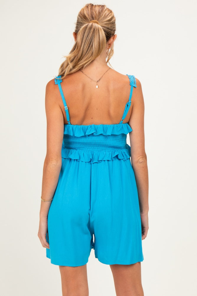 woman wearing a vibrant blue maternity romper with smocked bodice and ruffle details, showing the back view