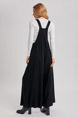 woman wearing a black maxi dress with adjustable straps and a relaxed fit, facing away from the camera
