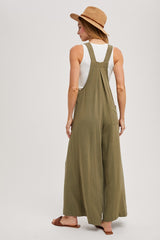 woman wearing a green long wide-leg jumpsuit and a tan hat, viewed from the back