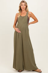 woman wearing a green maternity jumpsuit with adjustable straps and a baby bump visible