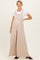 woman wearing a light beige maternity jumpsuit with adjustable straps and a flowy wide-leg style