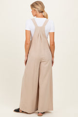 woman wearing beige maternity overalls with wide legs, shown from the back