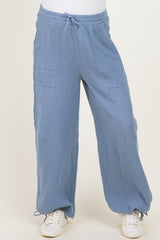 maternity wear in light blue loose fit pants with pockets and drawstring, model standing on neutral background