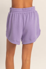 women wearing purple lightweight athletic shorts with an elastic waistband and side pockets, seen from the back