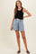 woman wearing a black ribbed tank top and denim maternity shorts with a drawstring waist