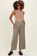 woman wearing a ribbed tan tank top and light green wide-leg maternity pants, accessorized with sunglasses