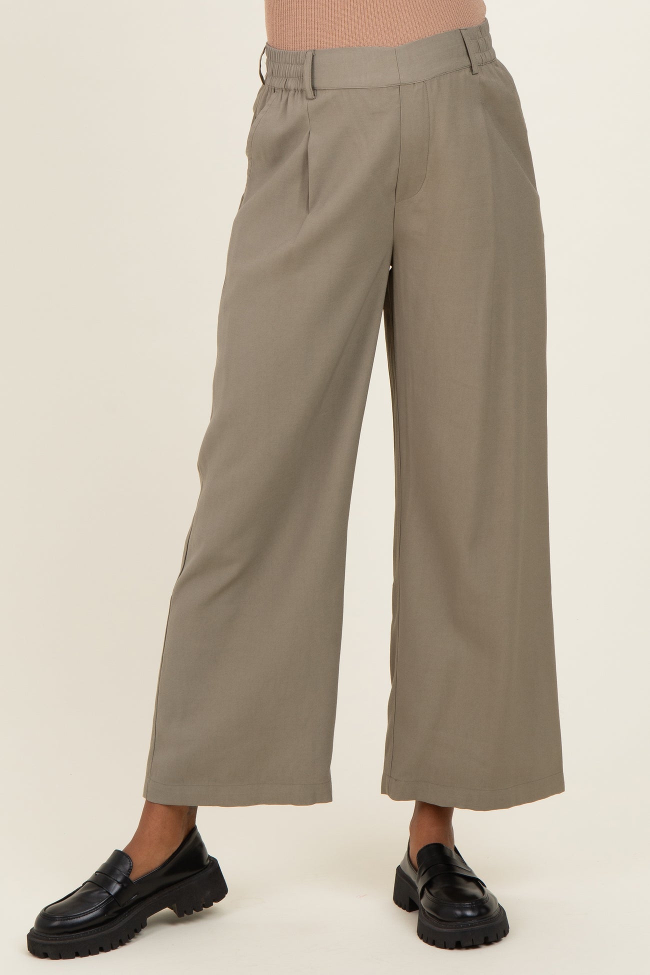 woman wearing a pair of beige maternity wide-leg trousers with an elastic waistband and black loafers