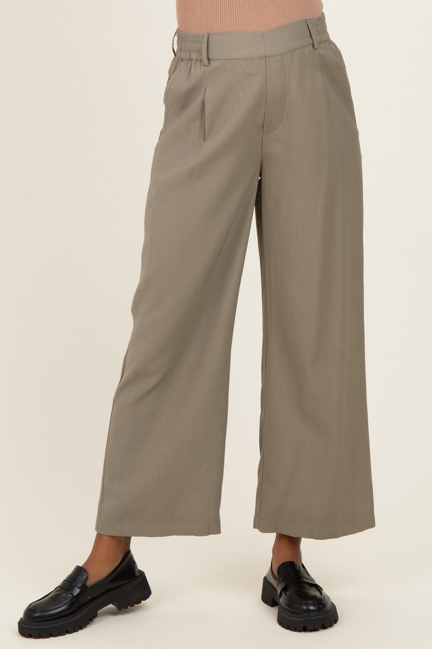 woman wearing a pair of beige maternity wide-leg trousers with an elastic waistband and black loafers