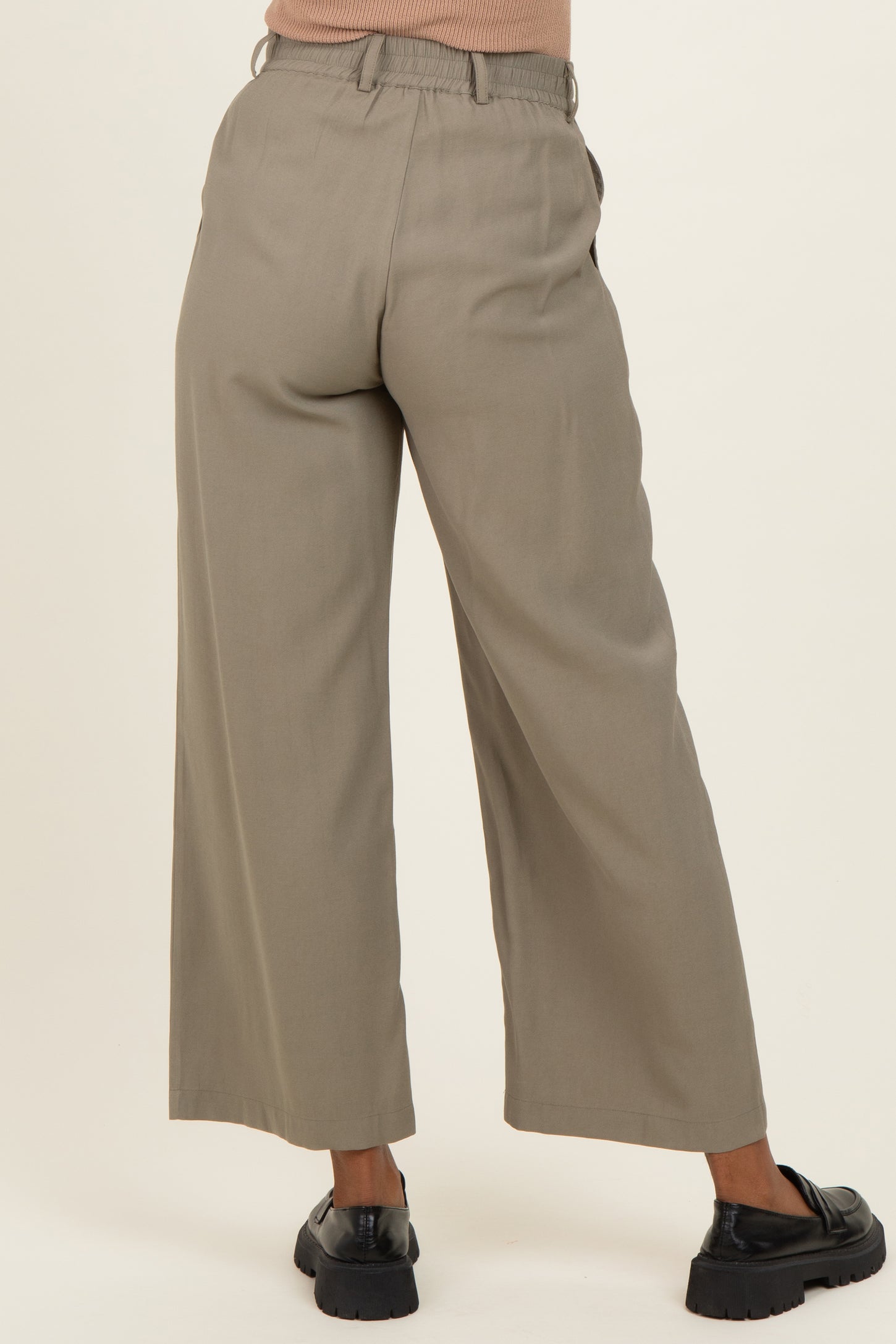 woman wearing light gray wide-leg maternity trousers with an elastic waistband and pockets, viewed from the back