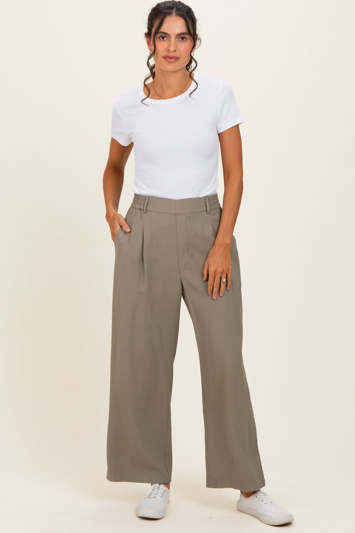 woman wearing a white short sleeve top and high-waisted khaki wide-leg pants with side pockets and white sneakers
