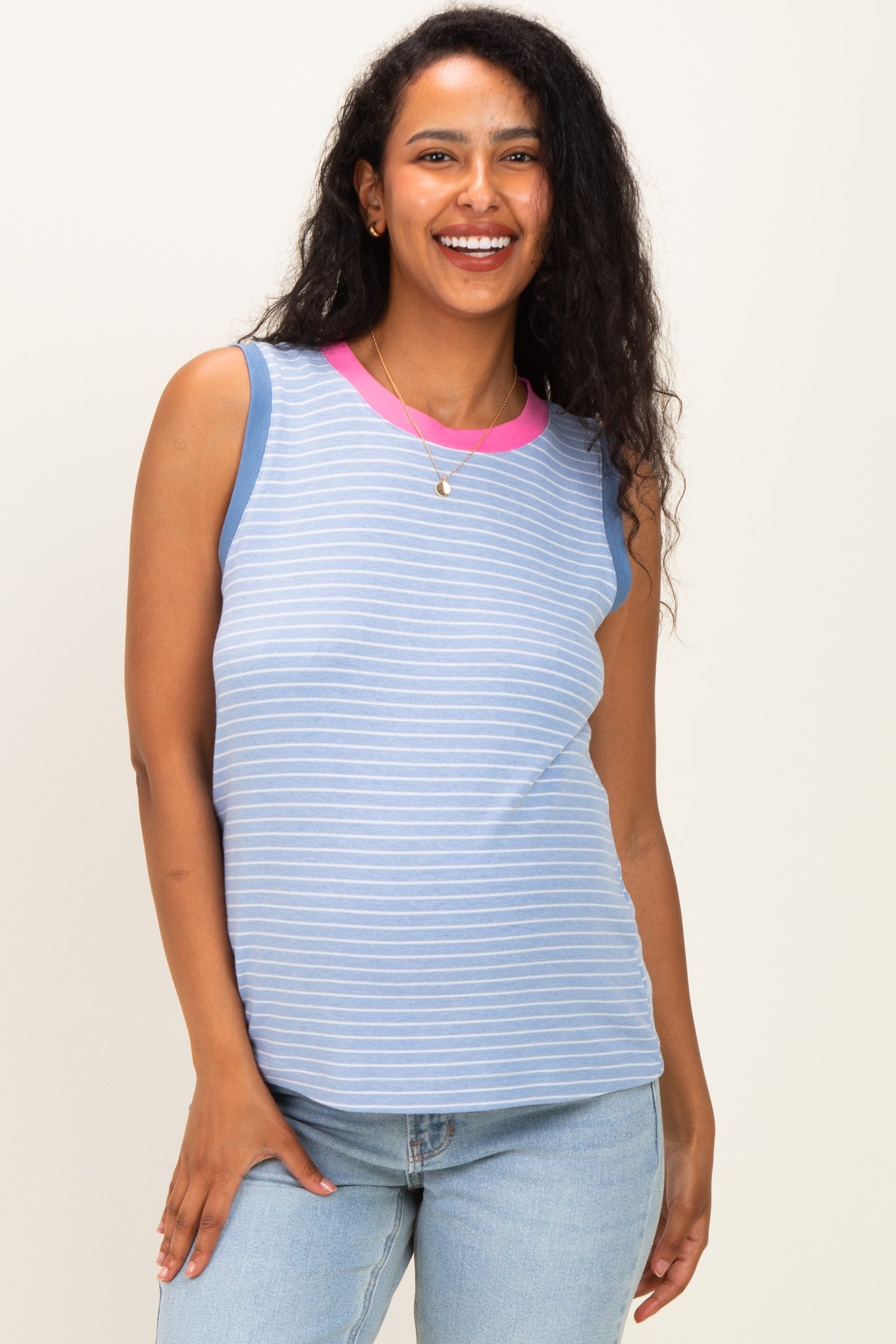 woman wearing a blue and white striped maternity tank top with pink neckline, smiling and standing casually