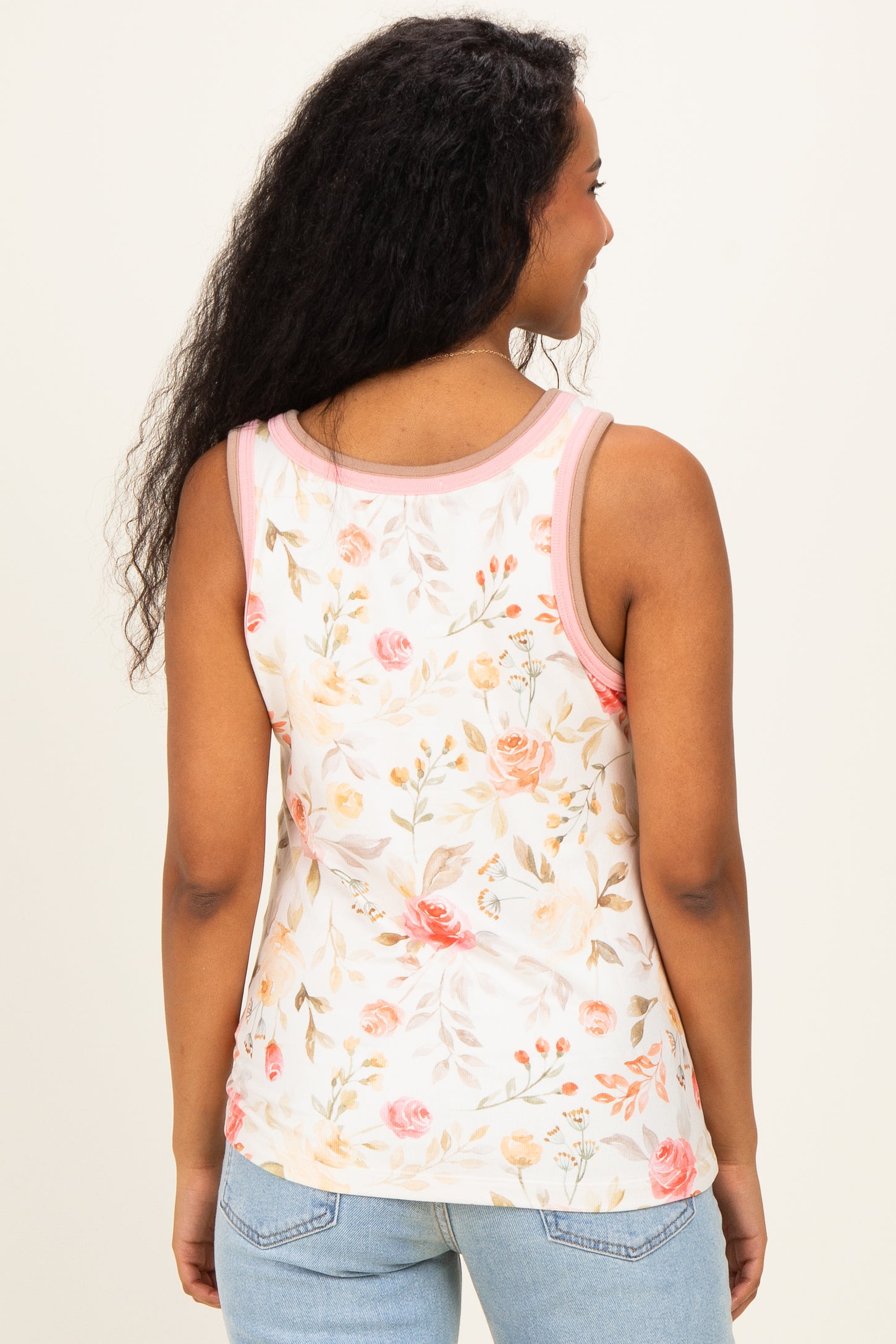 woman wearing a floral maternity tank top with pink trim, showing the back view against a plain background