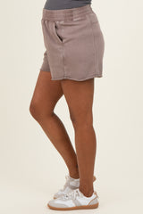 woman wearing light brown maternity shorts with an elastic waist and side pockets, styled with white sneakers