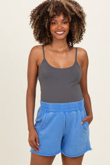 woman wearing a gray maternity tank top and blue maternity shorts with pockets, smiling at the camera