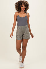 woman wearing a gray maternity tank top and light green shorts, walking and smiling