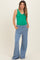 woman wearing a green maternity tank top and blue wide-leg maternity pants with pockets