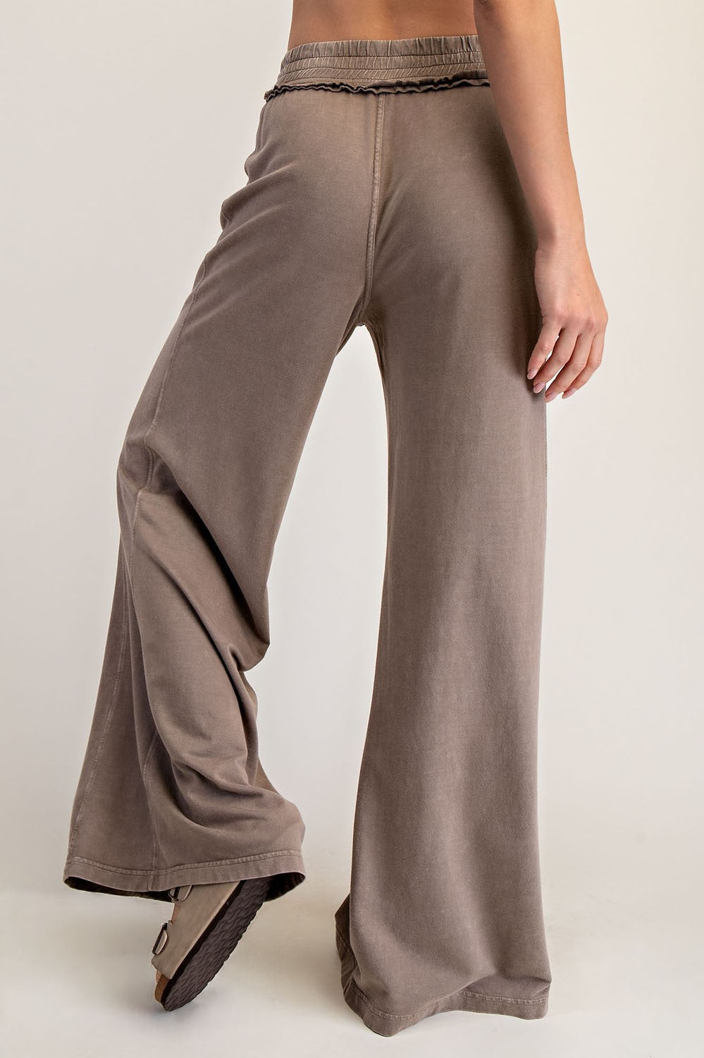 woman wearing taupe wide leg lounge pants with an elastic waistband and ruffle detail