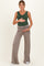 woman wearing a green sleeveless maternity top and beige wide-leg maternity pants, holding her baby bump