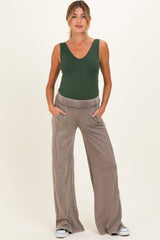 woman wearing a green maternity bodysuit and taupe wide-leg maternity pants with pockets