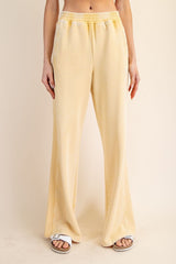 woman wearing light yellow wide-leg lounge pants with an elastic waistband and side pockets