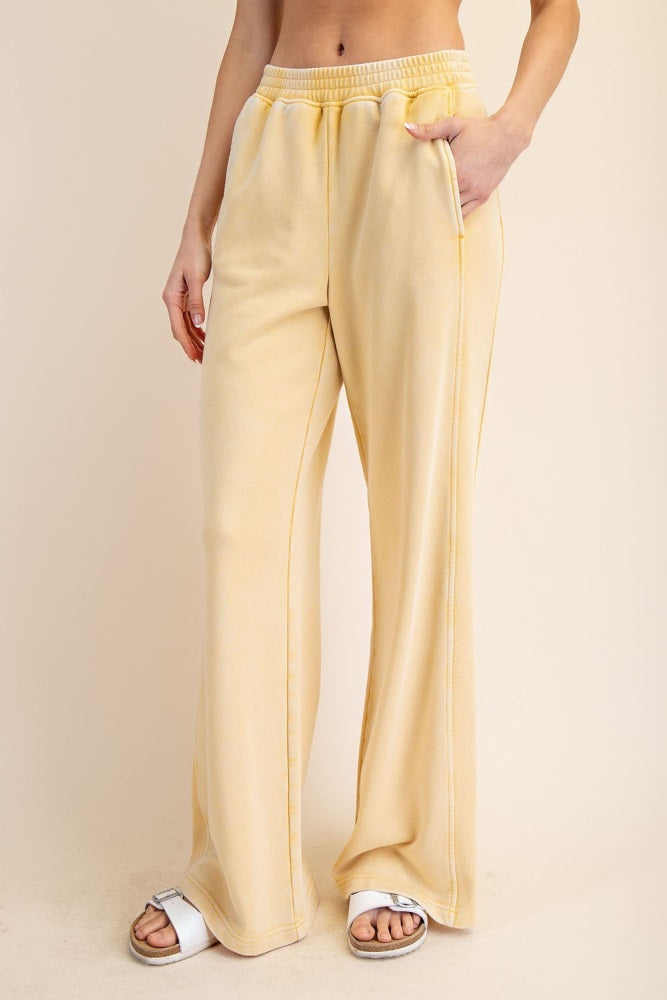 woman wearing pale yellow wide-leg lounge pants with side pockets and an elastic waistband