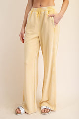 woman wearing pale yellow wide-leg lounge pants with side pockets and an elastic waistband
