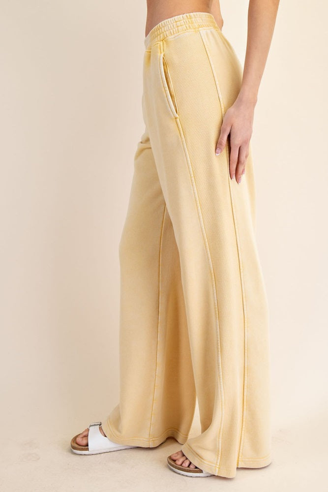 woman wearing pale yellow wide-leg sweatpants with a high waist and drawstring detail