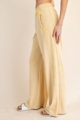 woman wearing pale yellow wide-leg sweatpants with a high waist and drawstring detail