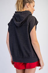 woman wearing a dark gray sleeveless hoodie with a hood and red shorts, viewed from the back