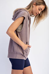 woman wearing a taupe sleeveless hoodie with a front pocket and styled with navy bike shorts