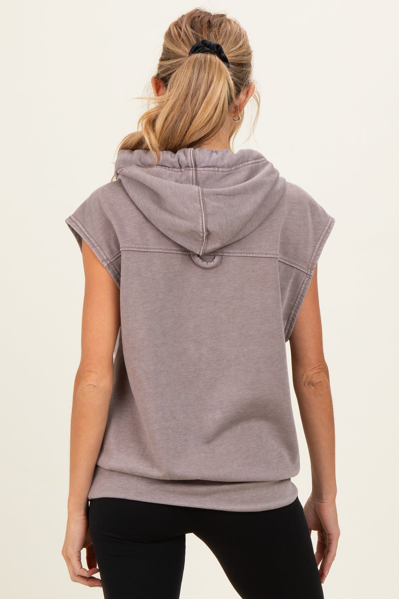 woman wearing a taupe sleeveless maternity hoodie with a hood, viewed from the back