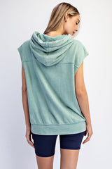 woman wearing a green sleeveless hoodie with a hood and a relaxed fit, paired with navy bike shorts