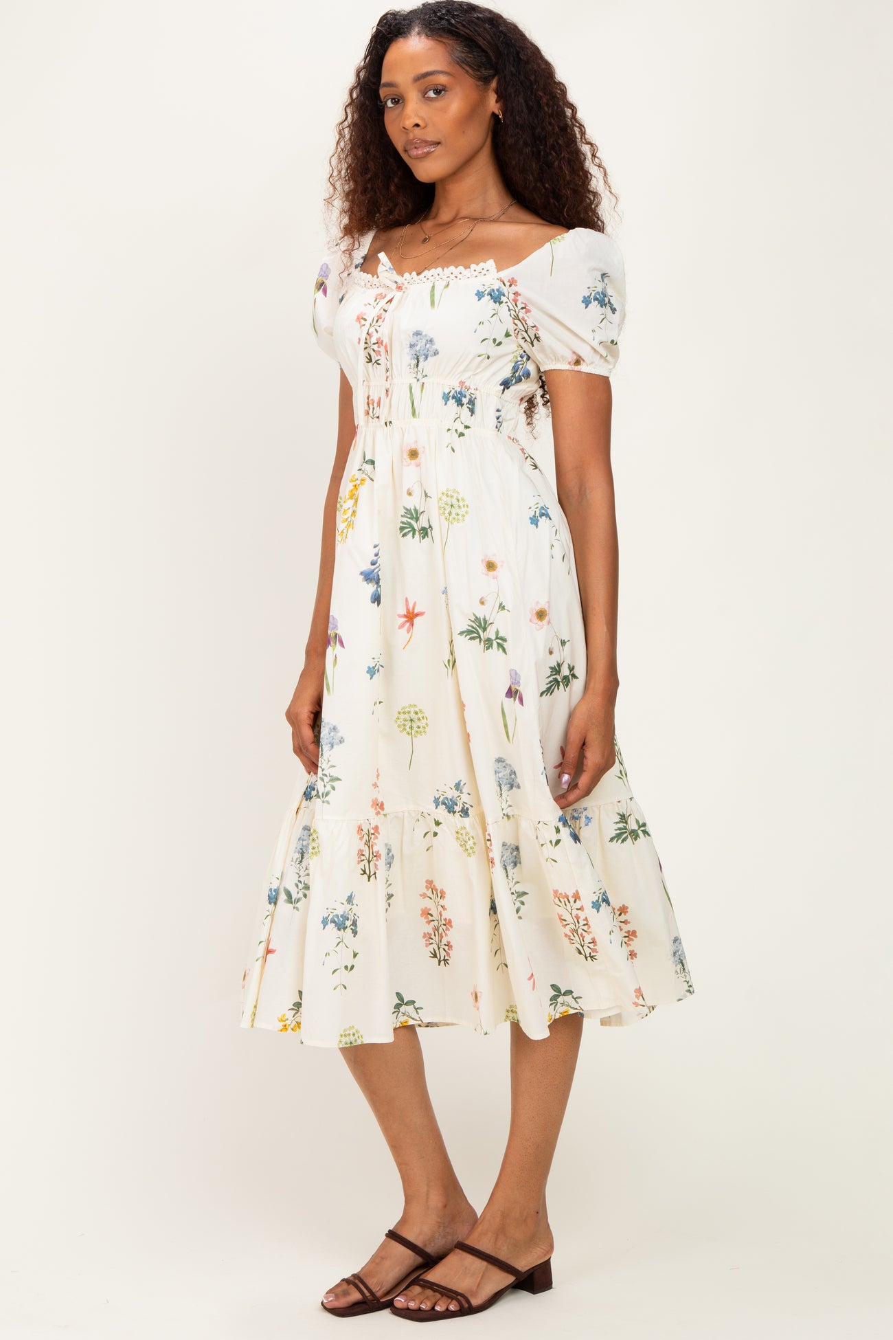 woman wearing a floral print midi dress with puff sleeves and a tiered skirt in white