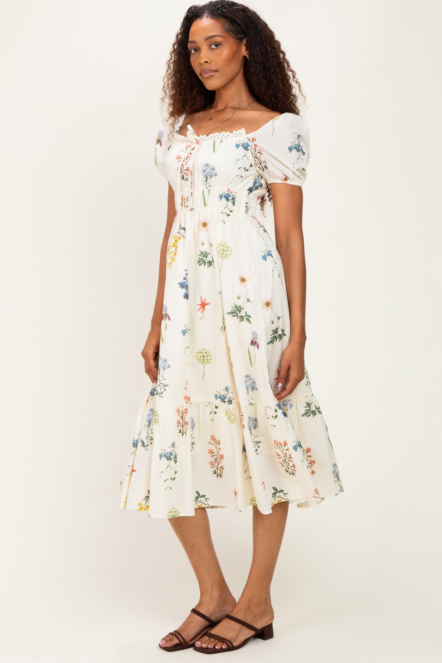 woman wearing a floral print midi dress with puff sleeves and a tiered skirt in white