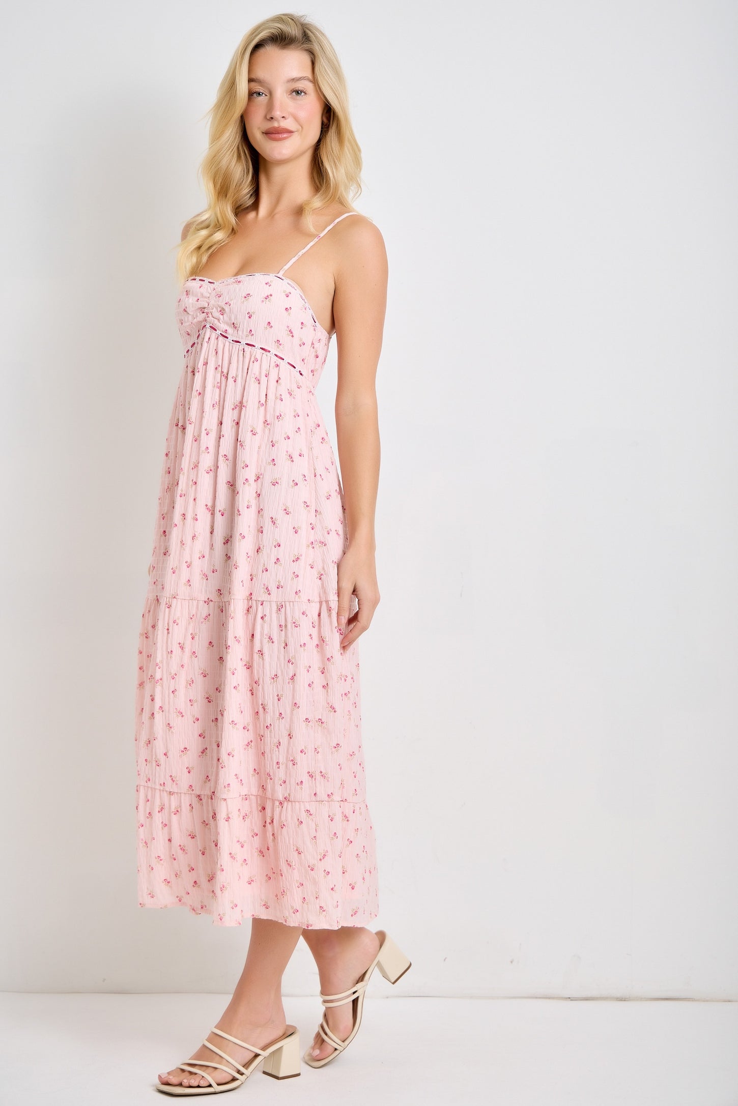 woman wearing a pink floral maxi dress with spaghetti straps and a tiered skirt