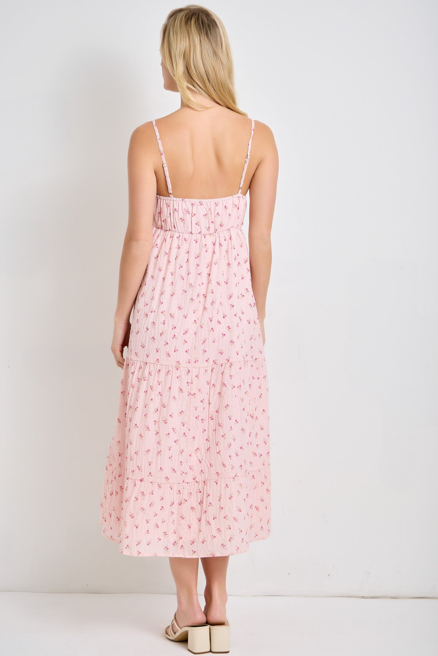 woman wearing a back view of a pink floral maxi dress with adjustable spaghetti straps and tiered skirt