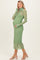 woman wearing a sheer green maternity dress with white polka dots and long sleeves, showing her baby bump