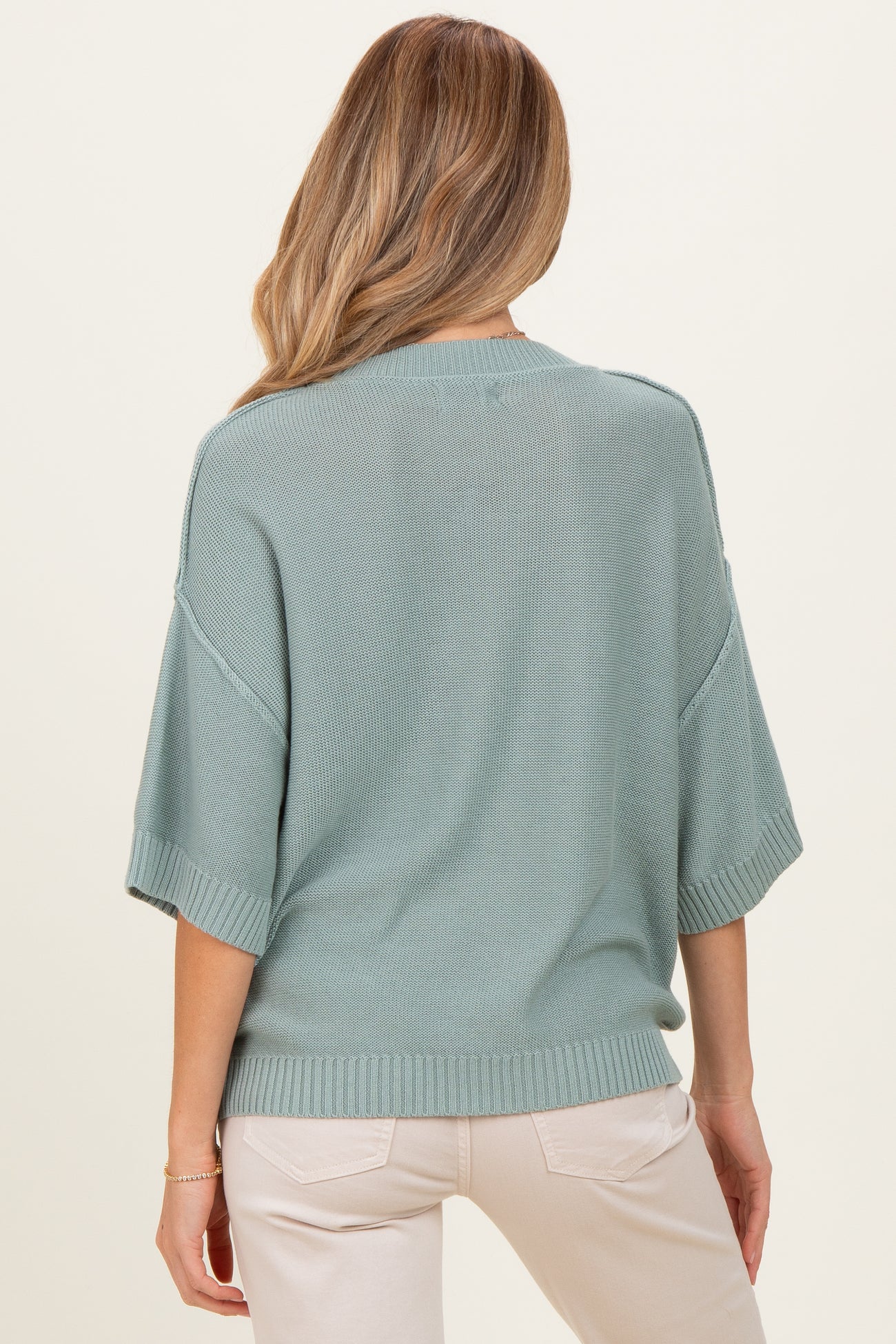 woman wearing a relaxed fit light green maternity sweater with short sleeves, seen from the back