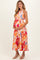 woman wearing a colorful floral maternity dress and holding her baby bump