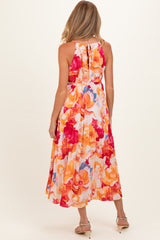 woman wearing a vibrant floral maternity maxi dress with a tie-back detail