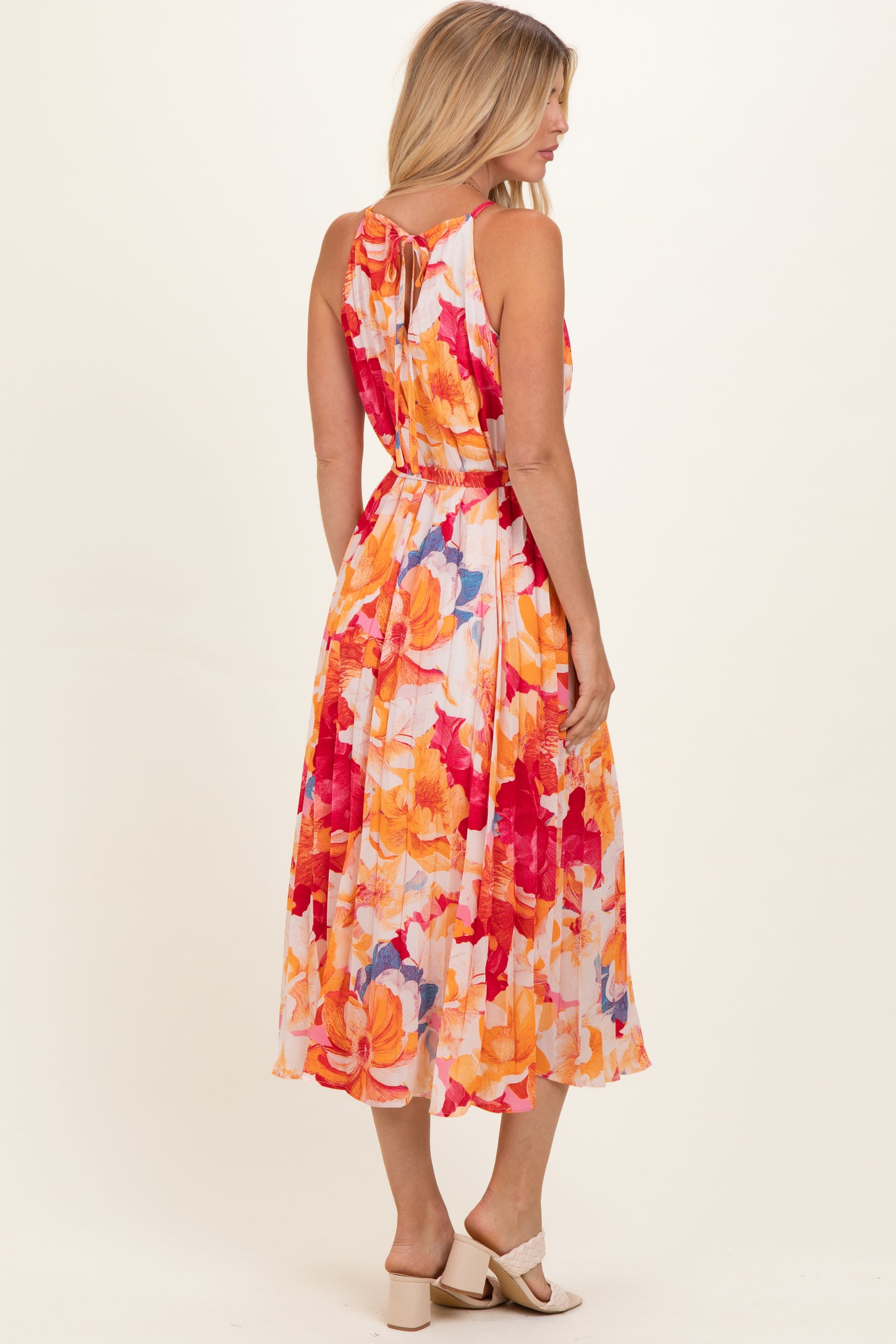 woman wearing a colorful floral maxi dress with a tie back detail
