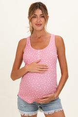 woman wearing a pink maternity tank top with a floral pattern and holding her baby bump