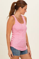 woman wearing a pink tank top with a floral print and buttons, paired with denim shorts