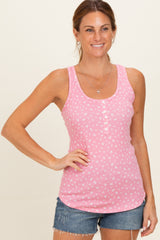 woman wearing a pink sleeveless tank top with a button detail and floral print, paired with denim shorts