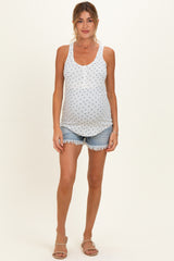 woman wearing a light blue maternity tank top with a floral pattern and denim shorts, showcasing her baby bump