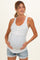 woman wearing a white maternity tank top with a blue floral print, holding her baby bump, paired with denim shorts