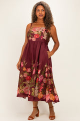 woman wearing a burgundy floral plus size midi dress with a fitted bodice and pockets, styled with brown heeled sandals