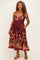 woman wearing a burgundy floral plus size midi dress with a fitted bodice and pockets, styled with brown heeled sandals