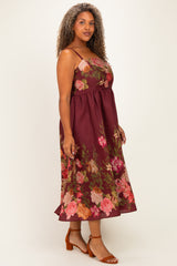 woman wearing a burgundy floral midi dress with thin straps and a flowy skirt, styled with brown heeled sandals